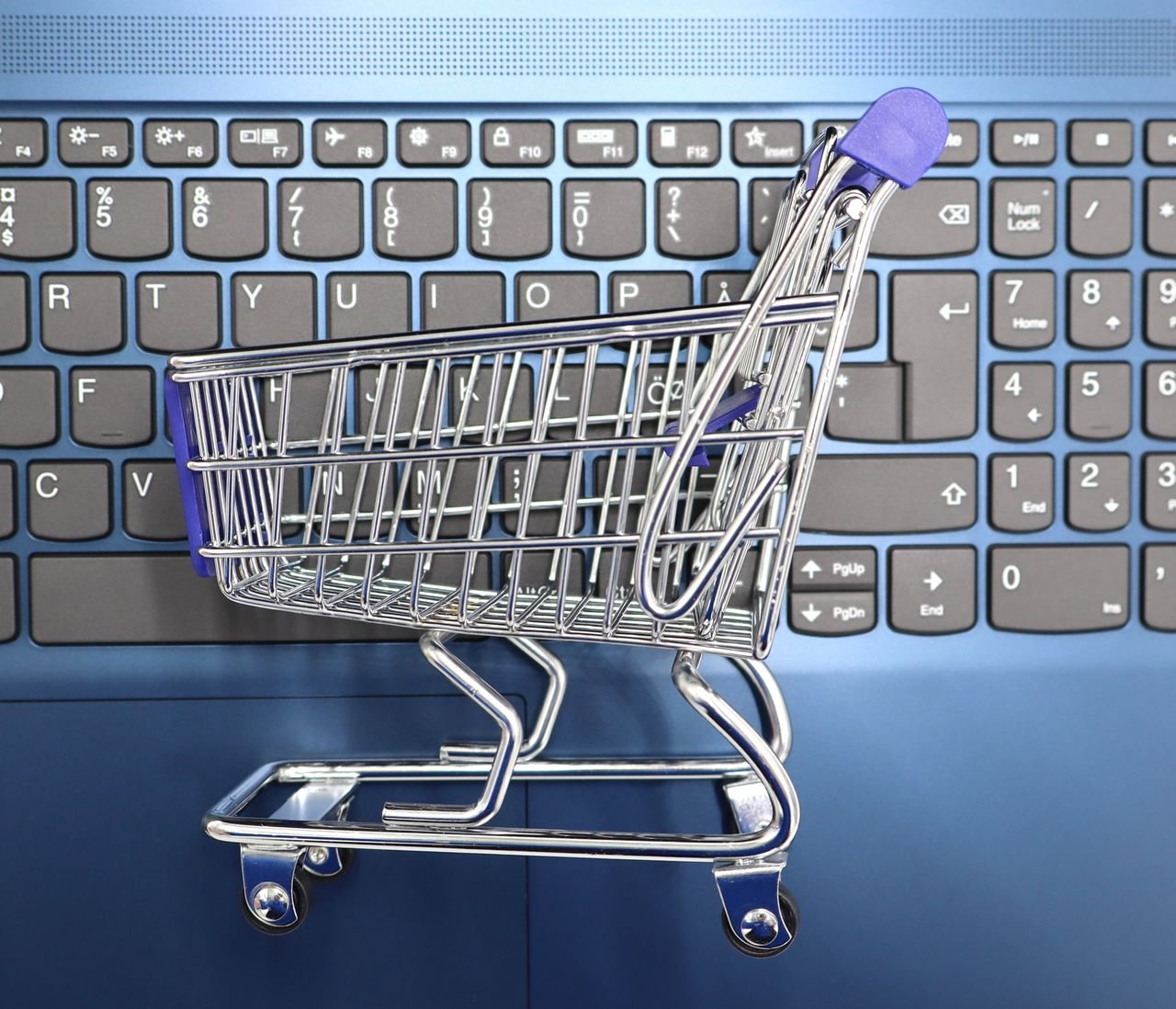 The Art of Drawing Readers In: Your attractive post title goes here A miniature shopping cart placed on a laptop keyboard symbolizing online shopping and e-commerce.